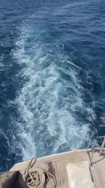 Mavi denizde, ufukta şehir manzarası olan bir tekne uyanır..