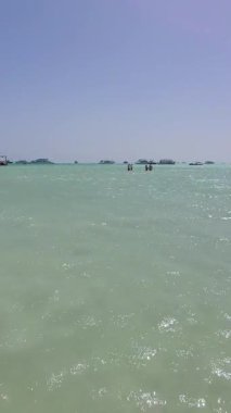 Mısır 'da Kızıldeniz' in sığ sularında arka planda yatlarla yürüyen iki çift..