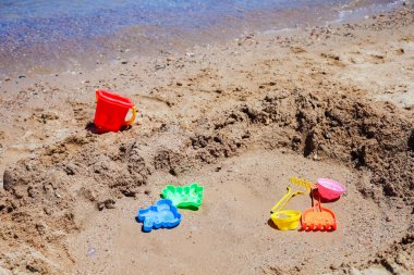 Güneşli sahil sahilinde renkli kum oyuncakları.