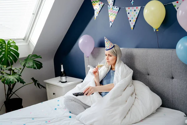 Droevige Vrouw Pyjama Feestmuts Drinkt Champagne Kijkt Gewikkeld Een Deken — Stockfoto