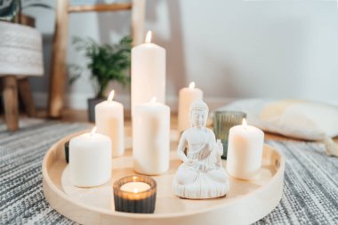 Ahşap tepside yanan mumlar ve modern Scandi 'nin içinde beyaz Buda heykelciği. Meditasyon için Zen kompozisyonu, yoga pratiği, rahatlama. Denge ve sakin enerji akışı kapalı alanda