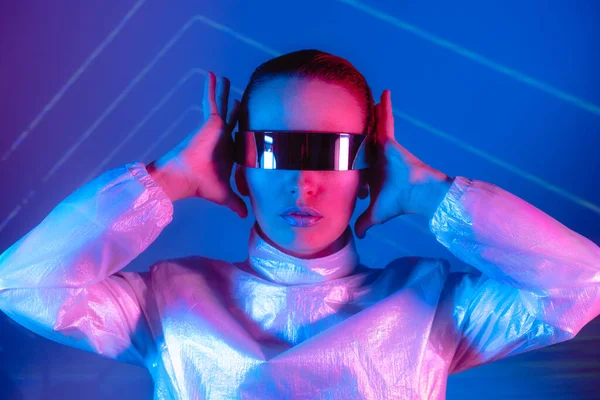 Neon portrait of woman, dressed in futuristic holographic clothes and glasses. Portrait of a cyberpunk girl. Neon blue and pink light. Virtual reality glasses. Fashion, futuristic generation concept