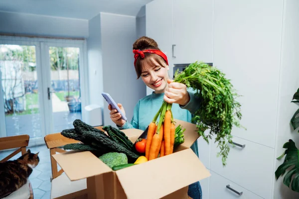Young Woman Examines Fresh Organic Carrots Her Online Food Delivery — Stock Photo, Image
