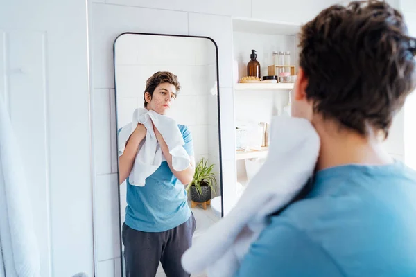 여드름 문제가 우울증에 소년은 집에서 얼굴의 피부를 돌본다 거울을 수건으로 — 스톡 사진