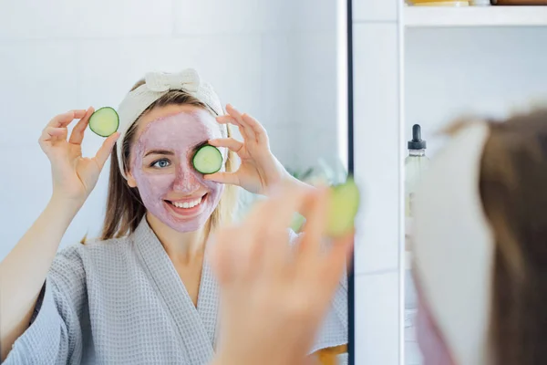 Yüzünde Pembe Kilden Maske Olan Genç Bir Kadın Banyoda Salatalık — Stok fotoğraf