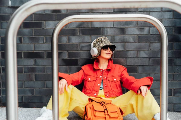 패션을 선글라스를 양동이 모자를 이어폰을 가까이에 자전거 스탠드를 도시의 길거리 — 스톡 사진