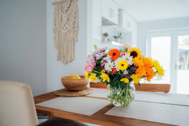 Mutfak tezgahında, üzerinde kocaman çok renkli vazolar olan çeşitli çiçek buketleri olan, modern, rahat, beyaz mutfağın bulanık arka planına sahip vazolar. Ev dekorasyonu detayları. Anneler Günü. Boşluğu kopyala
