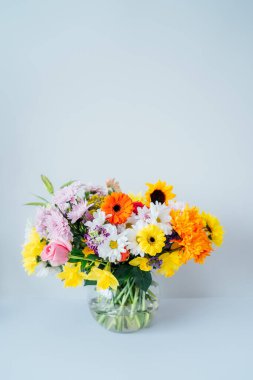 Yuvarlak vazo, açık gri, beyaz arka planda çeşitli karışık çiçek buketleriyle. Çiçek vermek. Anneler günü, kadınlar günü, sevgililer günü, doğum günü hediyesi. Dikey kart. Boşluğu kopyala.