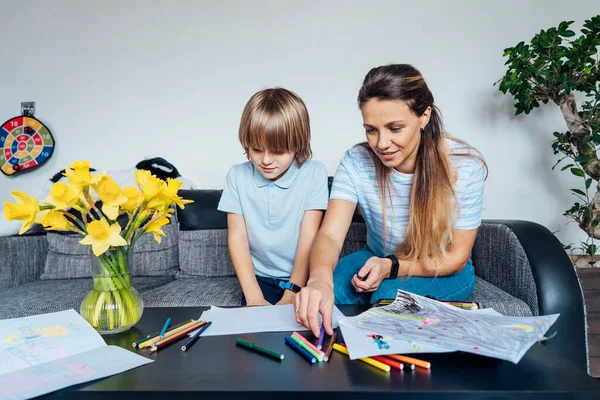 リビングルームで色鉛筆やマーカーで母と息子の図面 笑顔の母親は 家庭の週末に息子と紙の上でペイントを楽しむ 子供の創造性の概念を持っています 選択的焦点 — ストック写真