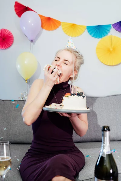 Woman Festive Dress Party Cap Eating Birthday Cake Her Hands — Stock Photo, Image