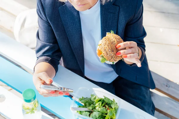 Femme Affaires Cultivée Manger Hamburger Complet Avec Salade Utilisant Téléphone — Photo