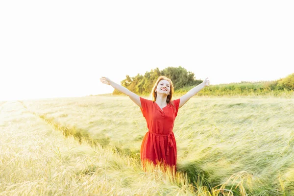 夕暮れ時には小麦畑で腕をリラックスしている幸せな若い女性 自由を祝う 肯定的な感情の生活 心の平和を感じる 精神衛生の練習 自然のリラックス 選択的焦点 — ストック写真