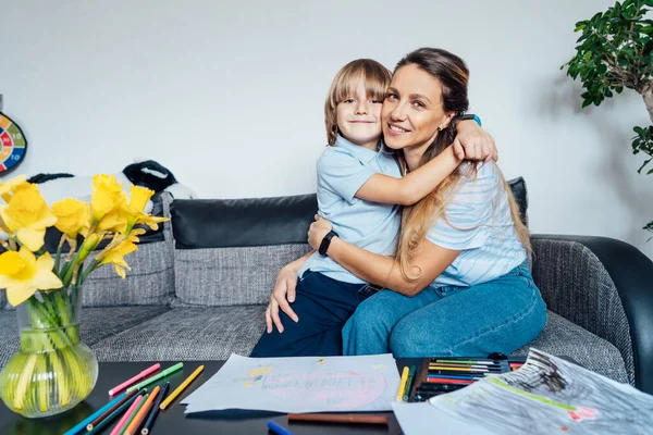 笑顔の息子の肖像画は 自宅の家族の週末の間に彼の幸せな母親を抱いて母と息子のリビングルームで色鉛筆やマーカーで描画します 子供の創造性の概念 選択的焦点 — ストック写真