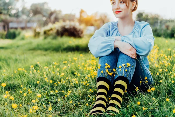 청바지와 무늬가 검은색 노란색 양말을 착용하고 초원의 잔디에 암컷을 꽃피는 — 스톡 사진