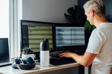 Bilgisayarda çalışan delikanlının masasındaki kurutulmuş kuru yemekle karıştırıcıya odaklan. Bilgi teknolojileri uzmanı iş sırasında yemek yiyor. Besin açısından dengeli beslenme diyeti. Yiyecek değişimi. Biyohack işlemi.