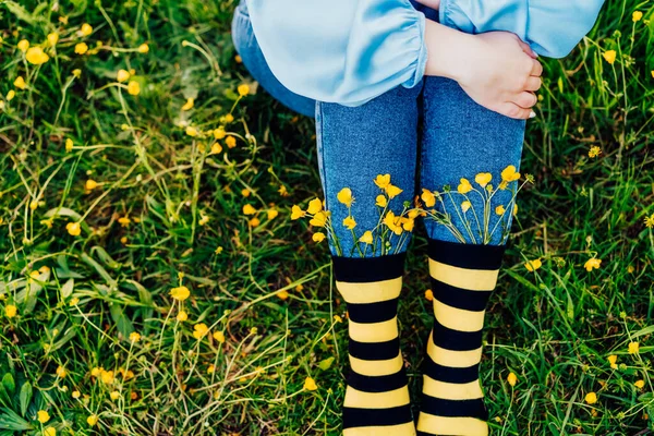 청바지와 무늬가 검은색 노란색 양말을 착용하고 초원의 잔디에 암컷을 꽃피는 — 스톡 사진