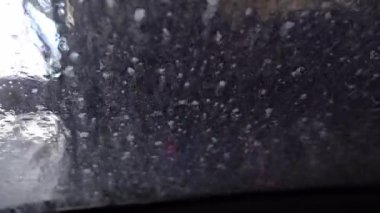 Kapalı bir oto yıkamadan geçerken ön camdan dışarı bakan sürücü görüntüsü, otomatik oto yıkama servisi. İç görünüm.