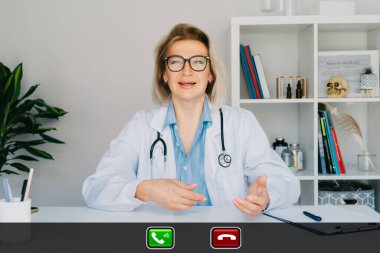 Orta yaşlı kadın doktorun bilgisayarda müşteriyle konuşması, kadın hemşirenin hasta hastayla konuşması, bilgisayar kullanması. Teletıp konsepti. Uzaktan kumandalı tıbbi randevu.