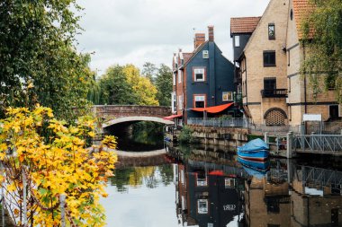 Houses and boats on the river Yare at Norwich city centre in Norfolk in autumn. Townhouses Buildings At Waterfront. Suburb Houses And Residential Building Near River In Europe. Selective focus