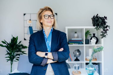 Gülümseyen 50 'lerin şık, kendine güvenen iş kadını, orta yaşlı şirket CEO' su, modern ofiste kıdemli bayan profesyonel koç takım lideri portresi. Kadın lider..