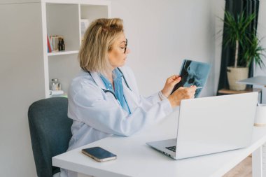 Kadın doktor online video görüşmesi yapıyor. Laptop 'ta hastaya danışıyor. Orta yaşlı kadın terapist ev içi sağlık tedavisi için video konferansı yapıyor. Teletıp konsepti. Uzaktan kumandalı tıbbi randevu.