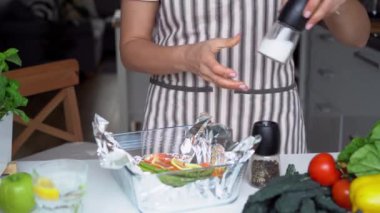 Yeşil kuşkonmaz tarifli fırında somon. Üçüncü adım. Somon ve sebzelere baharat ve tuz ekleyen bir kadın. Adım adım tarif et. Tarife göre evde sağlıklı yemekler.