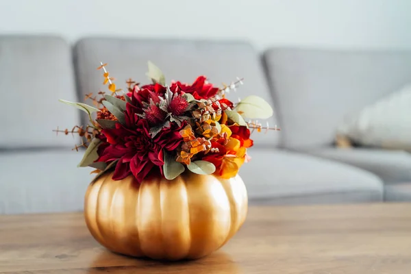 ゴールデンカボチャの花瓶の明るい人工花の秋の花束 ソファーの背景を持つリビングルームのインテリアの木製コーヒーテーブル 居心地の良い家の雰囲気のためのヒッグホームフォールデコレーション — ストック写真