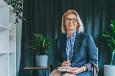 Gülümseyen 50 'lerin şık, kendine güvenen iş kadını, orta yaşlı şirket CEO' su, modern ofiste kıdemli bayan profesyonel koç takım lideri portresi. Kadın lider..