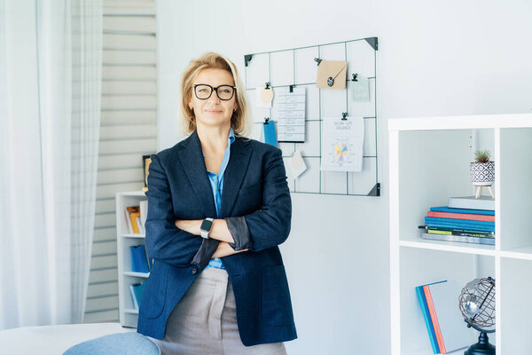 Smiling middle aged businesswoman near grid mood board with pinned work-life balance wheel diagram on her work space. Finding Balance in Your Life. Life planning. Coaching tools. Selective focus.