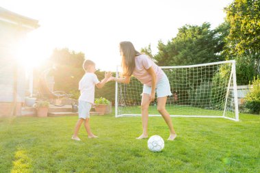 Bahçedeki futbol maçında genç bir anne ve oğul beşlik çakıyor. Mutlu bir aile futbol oynuyor, birlikte eğleniyor. Güneşli yaz gününde arka bahçede eğlenceli oyunlar oynardık. Annelik, çocukluk.