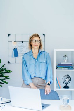 50 'lerin şık, kendine güvenen iş kadını portresi, orta yaşlı şirket müdürü, modern ofiste kıdemli bayan profesyonel koç takım lideri. Kadın bir lider. Dikey.