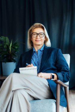 Gülümseyen 50 'lerin şık, kendine güvenen iş kadını, orta yaşlı şirket CEO' su, modern ofiste kıdemli bayan profesyonel koç takım lideri portresi. Kadın lider..