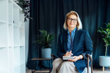 Gülümseyen 50 'lerin şık, kendine güvenen iş kadını, orta yaşlı şirket CEO' su, modern ofiste kıdemli bayan profesyonel koç takım lideri portresi. Kadın lider..