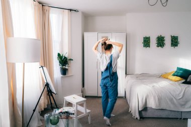 Dikiz aynasındaki kadın çizim kursuna gitmeyi planlarken aynaya bakıyor ve saçlarını topuz yapıyor. Tuvale resim çiziyorum. Evde dinleniyorum. Sanat, hobi, eğlence ve yaratıcı meslek kavramı.