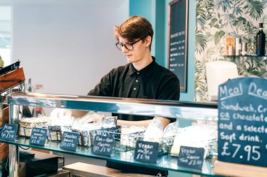 Genç bir garson, malları modern bir kahve dükkanında sergiliyor. Öğrenci kafede yarı zamanlı çalışıyor. İşsizlik sorunları ve gençler için iş olanakları. Küçük işletme boşlukları.