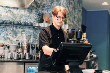 Genç garson, kafede müşteriye servis yapıyor. POS terminalinde çalışan bir adam. Yarı zamanlı çalışan bir öğrenci. İşsizlik sorunları ve gençler için iş olanakları. Küçük işletme boşlukları