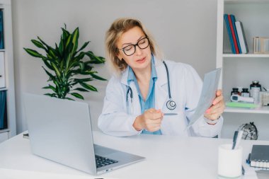 Kadın doktor online video görüşmesi yapıyor. Laptop 'ta hastaya danışıyor. Orta yaşlı kadın terapist ev içi sağlık tedavisi için video konferansı yapıyor. Teletıp konsepti. Uzaktan kumandalı tıbbi randevu