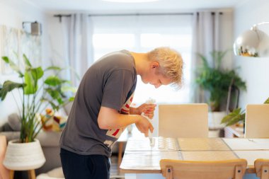 Yoğunlaşmış genç adam evdeki hafif modern mutfakta Fransız kurabiyeleri tatlısı yapmak için silikon pişirme tepsisine hamur işi koyuyor. Kurabiye pişirmek için adımlar hazırlıyorum. Mutfak hobisi. Seçici odak.