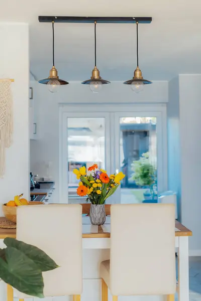 时尚和现代的Boho 丑闻内部的开放空间白色厨房与五颜六色的花在厨房柜台桌子上的花瓶 金黄色和工业风格的天花板灯 设计家居装饰 图库图片