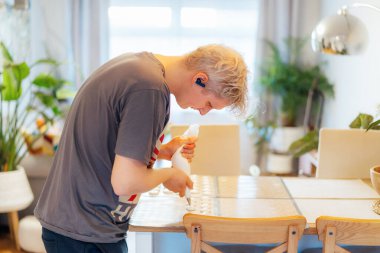 Yoğunlaşmış genç adam evdeki hafif modern mutfakta Fransız kurabiyeleri tatlısı yapmak için silikon pişirme tepsisine hamur işi koyuyor. Kurabiye pişirmek için adımlar hazırlıyorum. Mutfak hobisi. Seçici odak.