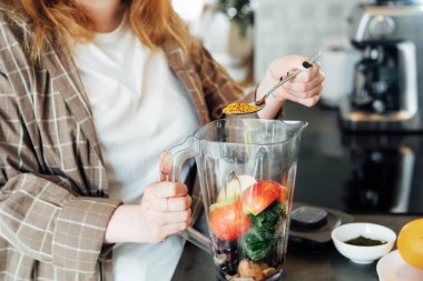 Mutfakta smoothie yaparken kadın arı poleni ekliyor. Süper gıda takviyesi. Sağlıklı detoks vegan diyeti. Sağlıklı beslenme, kilo verme programı. Seçici odak.