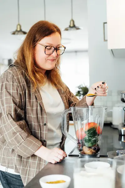 stock image Plus size young woman adding bee pollen during making smoothie on the kitchen. Superfood supplement. Healthy detox vegan diet. Healthy dieting eating, weight loss program. Selective focus.