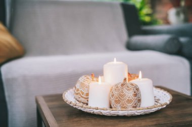 Sonbahar, Hygge Home doğal dekorunun rahat kompozisyonu. Balkabakları mandalalarla süslenmiş, oturma odasındaki sehpanın üzerinde yanan beyaz mumlar. Seçici odak