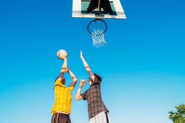 İki genç adam gün batımında parkta basketbol oynuyorlar. Basketbol maçında havada zıplayan arkadaşlar bir top için kavga ediyorlar. Gençlerin hobisi. Spor ve sağlıklı yaşam tarzı