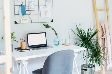 Modern Çağdaş iş yeri tasarımı. Bilgisayarlı beyaz masa, boş ekran, şifreli notlar ve planlar, yeşil santraller, ofis içi çalışma odasındaki ofis malzemeleri..