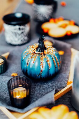 Evde rahat bir Cadılar Bayramı planı var. Dekoratif balkabağı, siyah fincanlarda sıcak çay içeceği sehpanın üzerindeki tabakta kurabiye ve tatlılar. Şenlikli sonbahar, güz havası ev dekorasyonu. Dikey kart