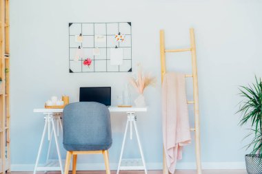 Ev ofis iş yeri tasarımı. Açık dizüstü bilgisayarı olan beyaz masa şeftali ve pembe renk paletli ızgara ruh hali tahtası ve mumlar gibi kadınsı dekorlar, kurumuş çiçekler. İlham ve ruh hali konsepti