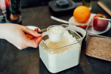 Mutfakta meyve püresi yaparken bitki bazlı bezelye proteini tozu alan kadını kapatın. Süper gıda takviyesi. Sağlıklı beslenme vegan diyeti. Sağlıklı beslenme, kilo verme programı.