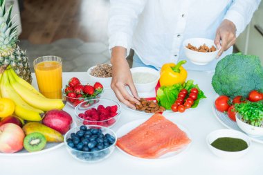 Kadın beslenme uzmanı besin oranlarına göre sağlıklı dengeli diyet tabağı yapar. Mutfak masasında meyve, sebze, tahıl ve protein içeren bir tabak.