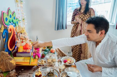 Geleneksel giyinmiş Hintli çift, kutlama sırasında Tanrı Ganesh için süslenip süslendikleri sunakta ibadet ediyorlar. Hint kültürü, Hint ritüeli ve gelenekleri